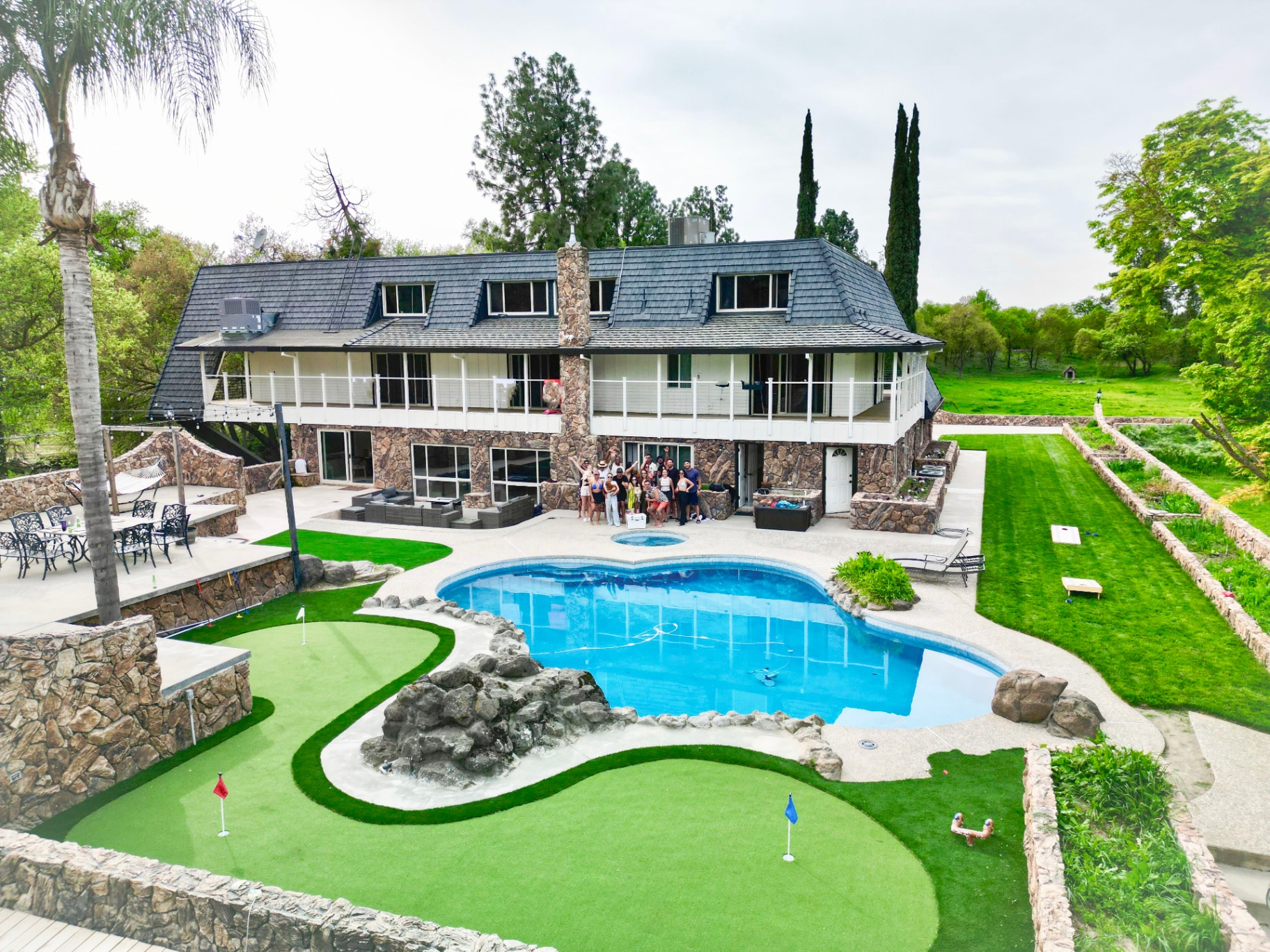 Group gathered on the back patio with pool, jacuzzi and putting green