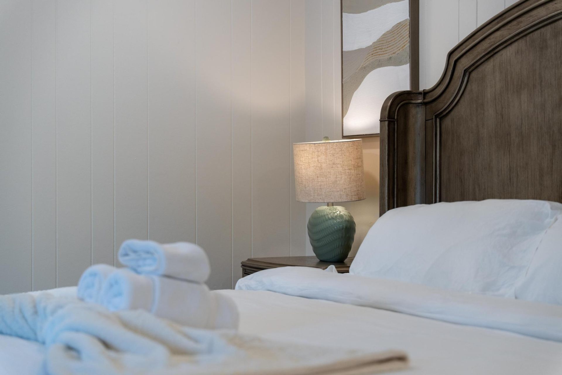 Bedside detail with linen lamp and carved headboard
