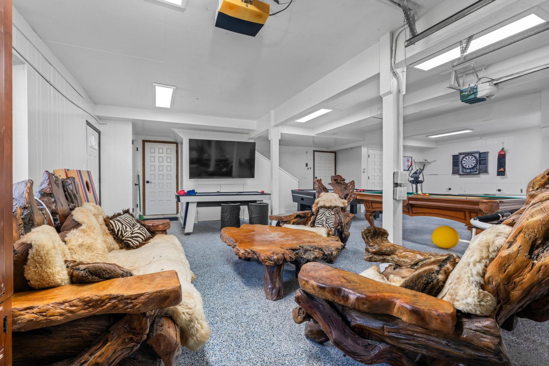 Downstairs game lounge with rustic live-edge seating, air hockey and pool