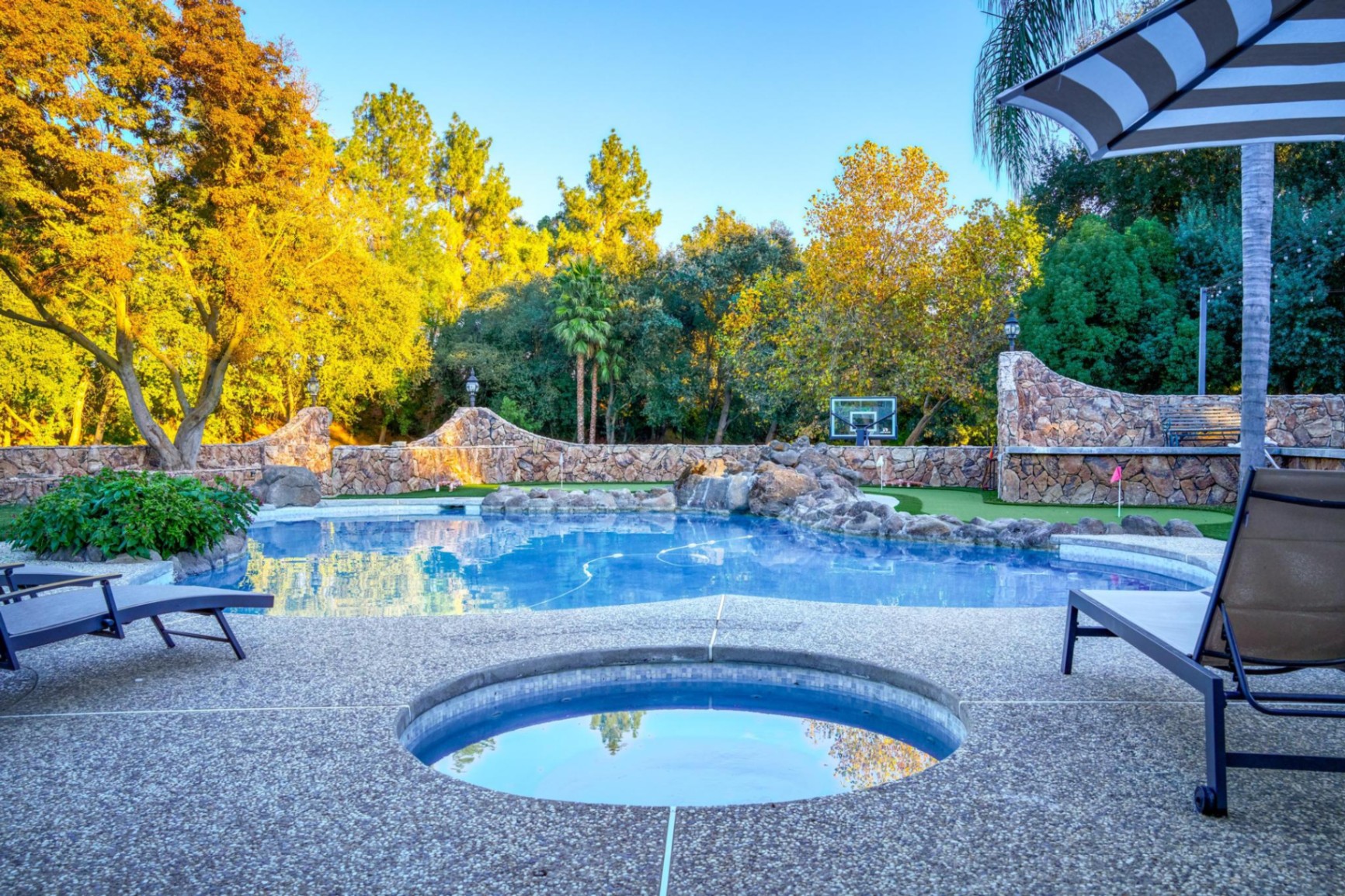 In-ground jacuzzi beside rock waterfall pool