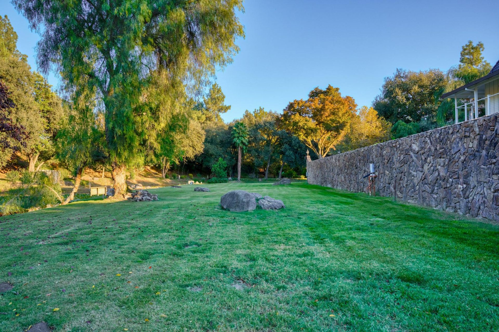 Expansive private lawn bordered by stone walls and mature oaks
