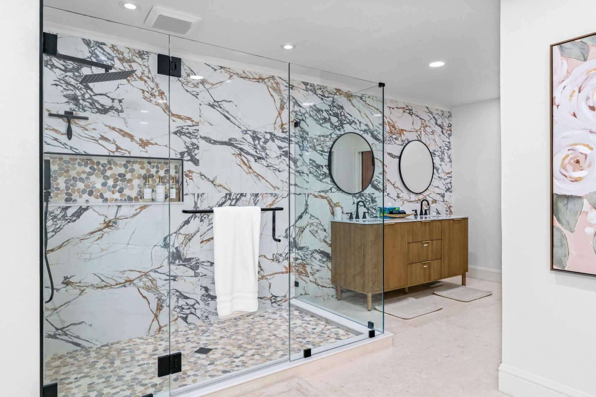 Walk-in marble shower with pebble mosaic floor