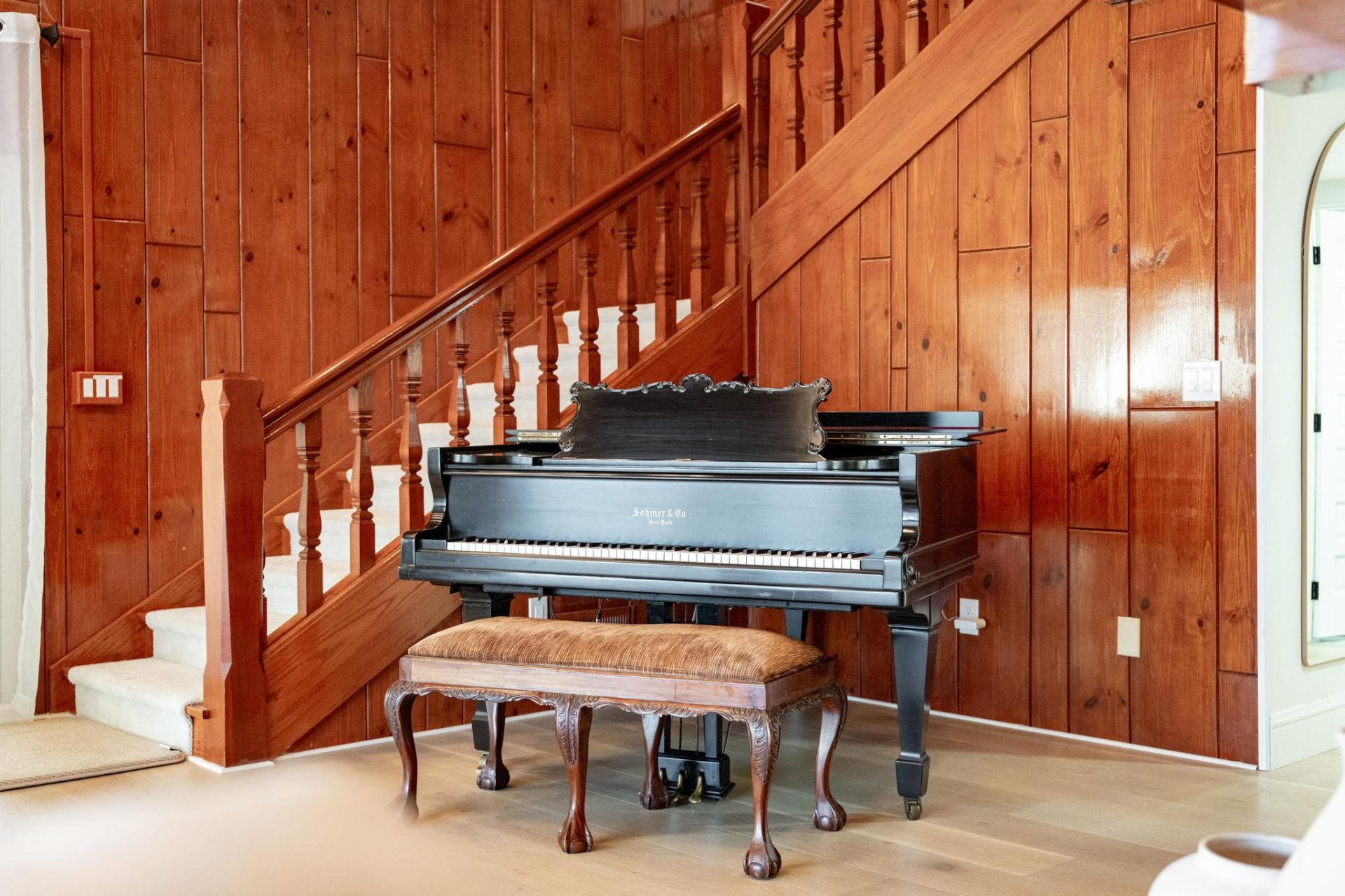 Antique Sohmer & Co grand piano beneath cherry-wood staircase