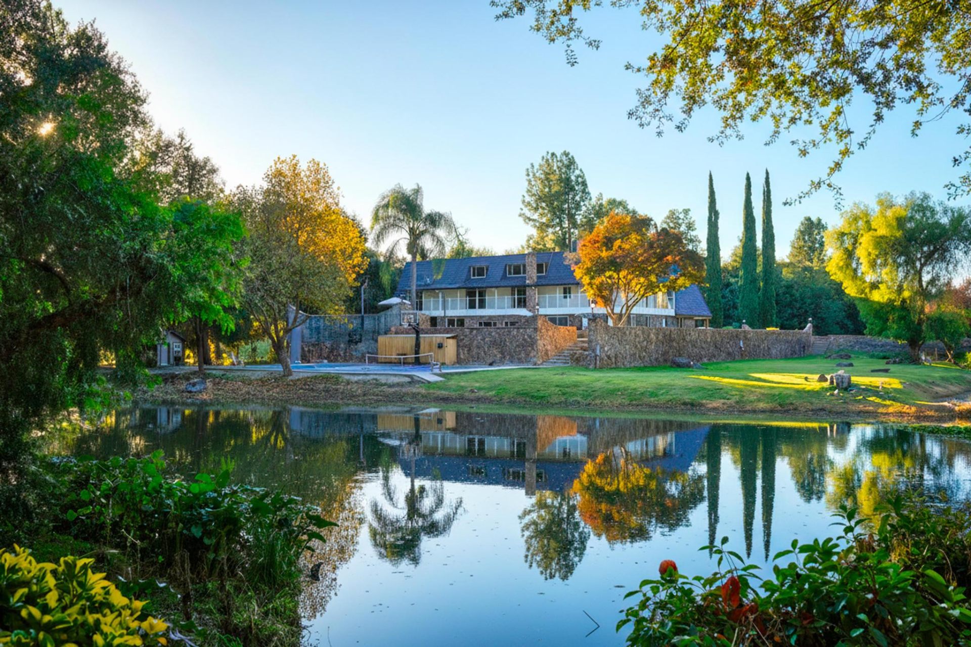 Estate reflected across the 2-acre stocked pond at sunset