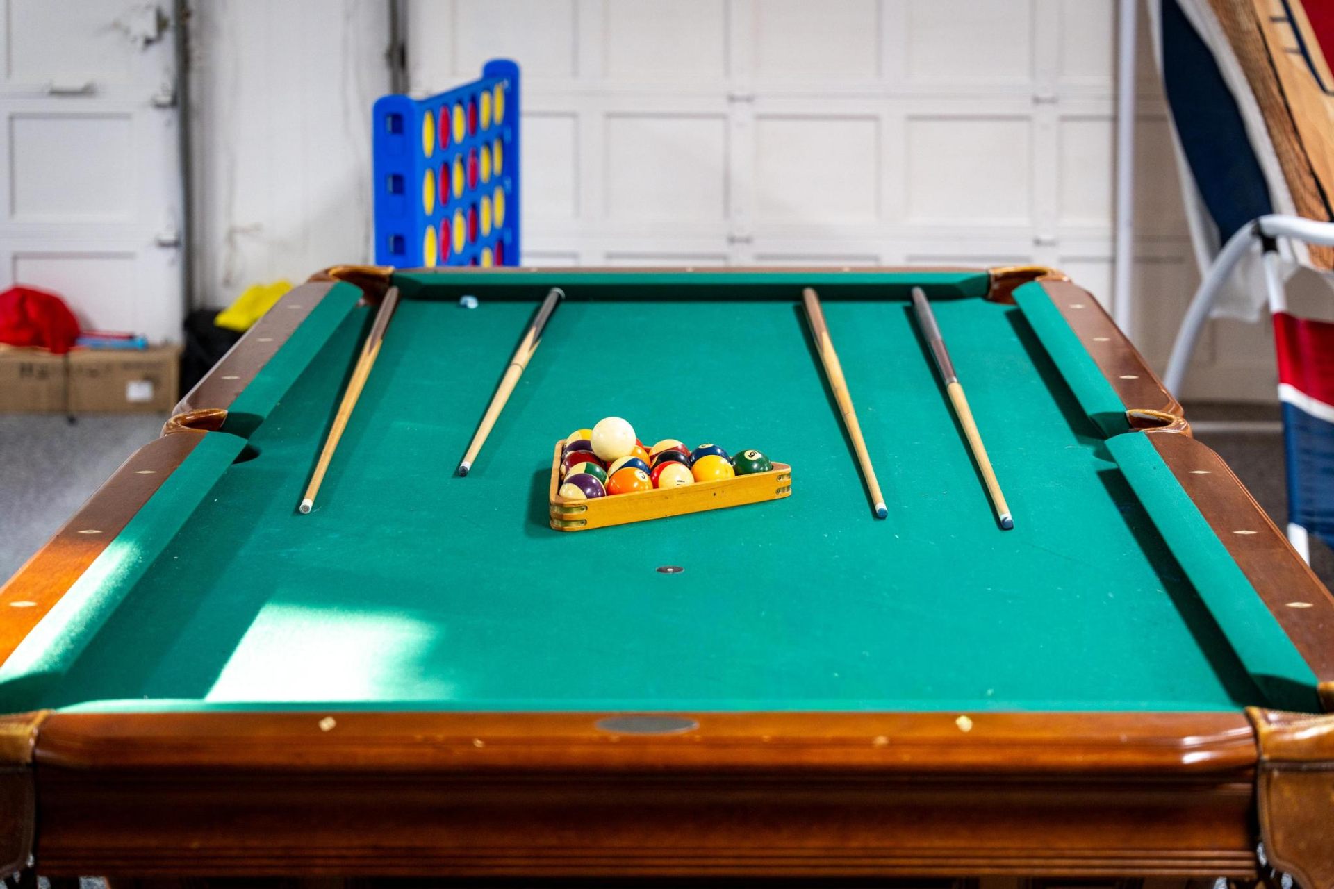 Pool table with cues and giant Connect Four in the game room
