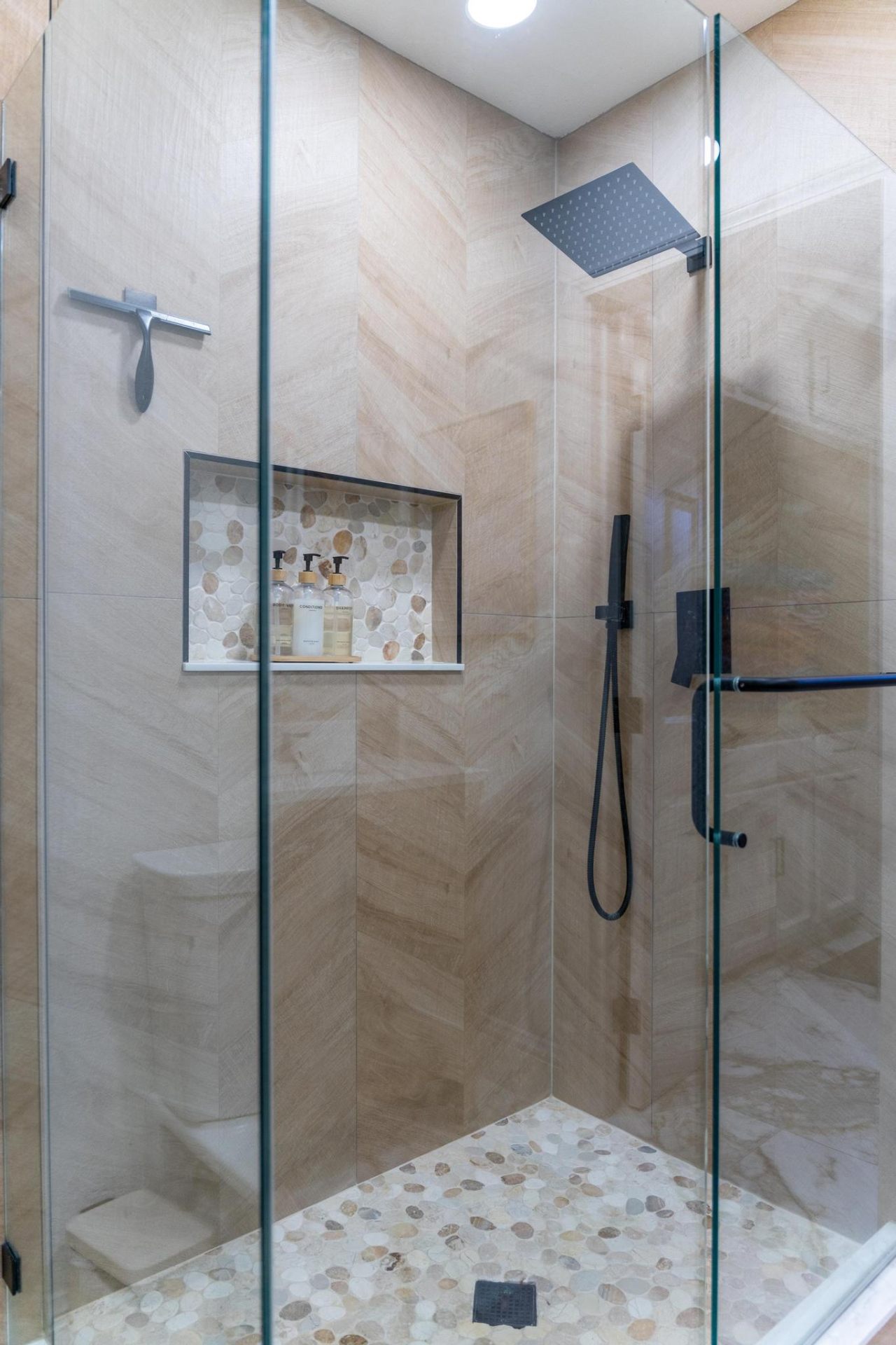 Chevron-tiled walk-in shower with pebble mosaic floor
