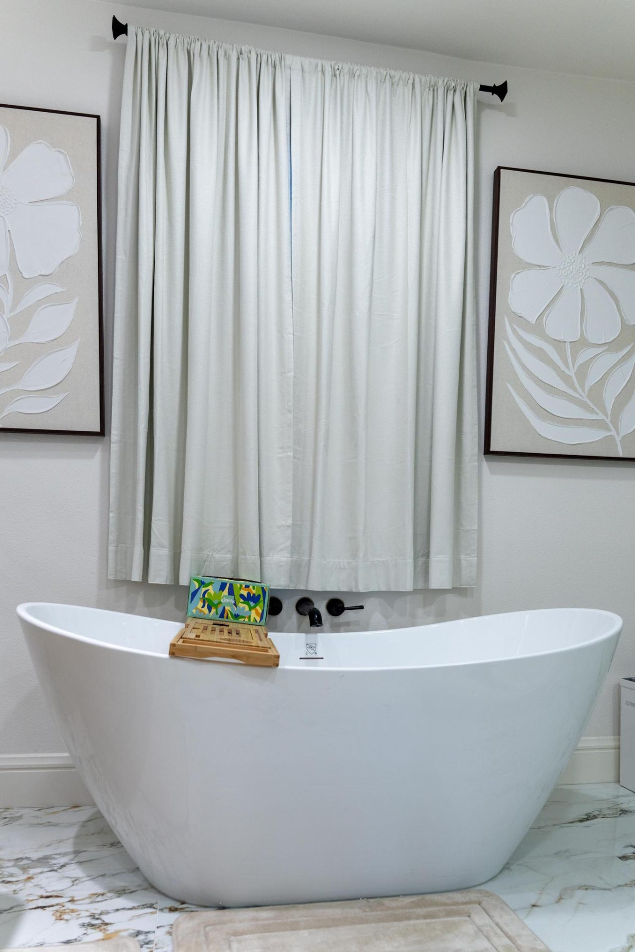 Freestanding soaking tub framed by floral artwork